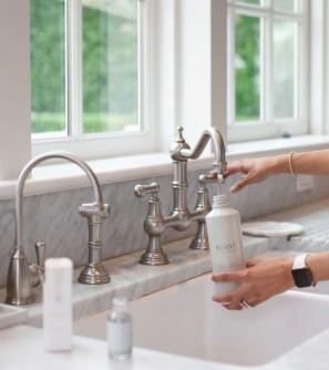 Hands at a kitchen sink with a bottle of soap