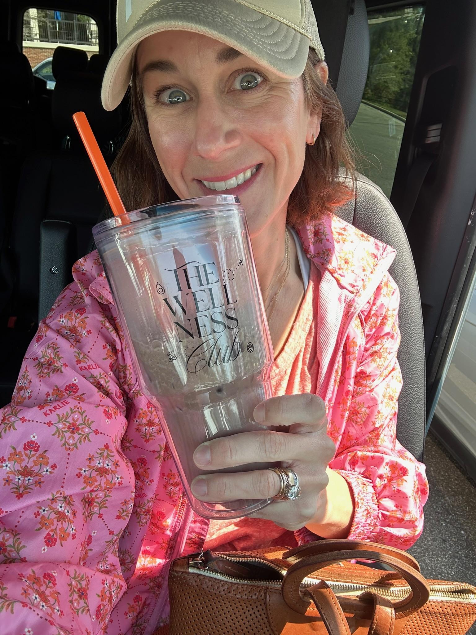 Louise in a pink floral jacket holding an iced drink